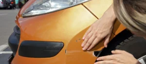 Rayure profonde sur la carrosserie d'une voiture dans un parking.